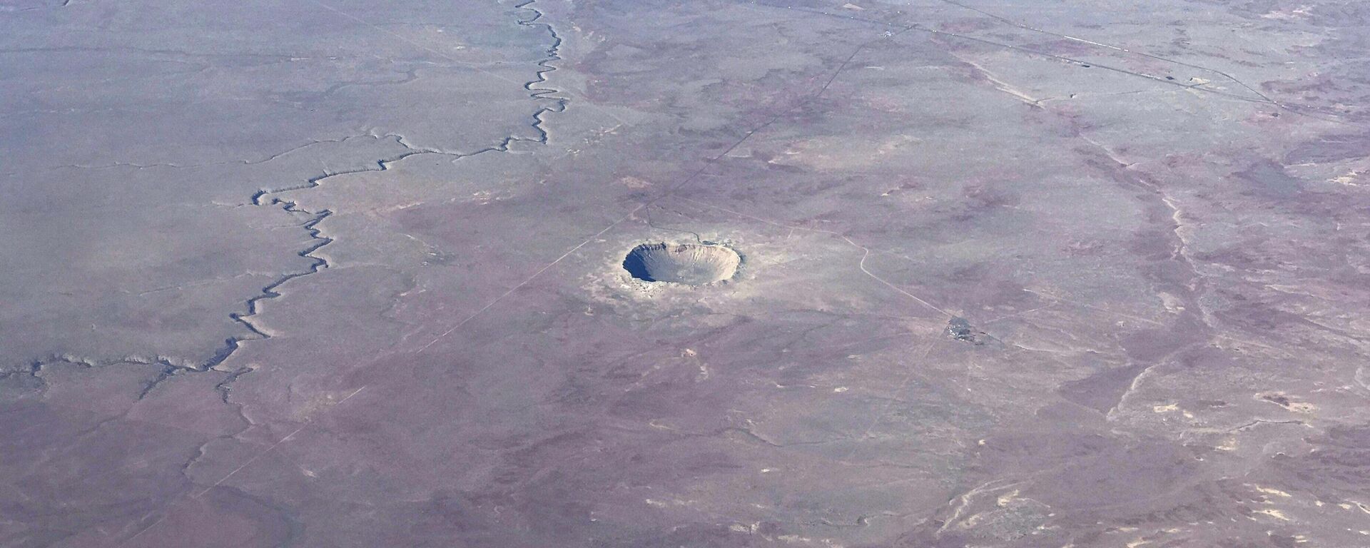 The Meteor Crater near Winslow, Arizona, is seen from a plane Januray 30, 2017. The Meteor Crater, sometimes known as the Barringer Crater and formerly as the Canyon Diablo crater, is a famous impact crater. It is the breath-taking result of a collision between an asteroid traveling 26,000 miles per hour and planet Earth approximately 50,000 years ago. Meteor Crater is nearly one mile across, 2.4 miles in circumference and more than 550 feet deep. - Sputnik India, 1920, 23.10.2023