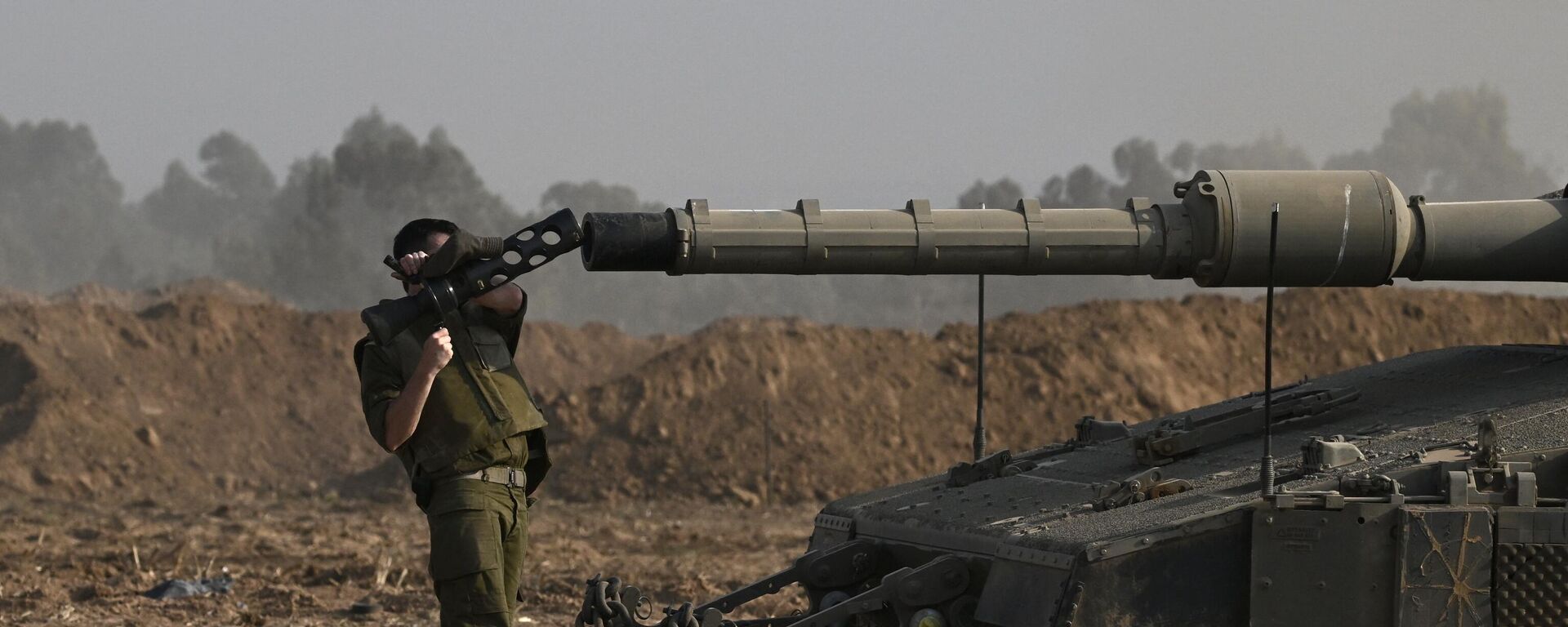 An Israeli solider checks the gun of a Merkava tank deployed along Israel's border with Gaza on October 24, 2023, amid the ongoing battles between Israel and the Palestinian group Hamas. - Sputnik भारत, 1920, 26.10.2023