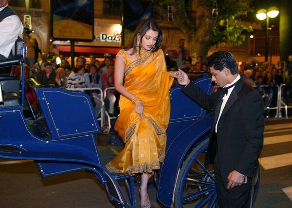 भारतीय अभिनेता शाहरुख खान भारतीय अभिनेत्री ऐश्वर्या राय को कोच से उतरने में मदद कर रहे हैं।  - Sputnik भारत