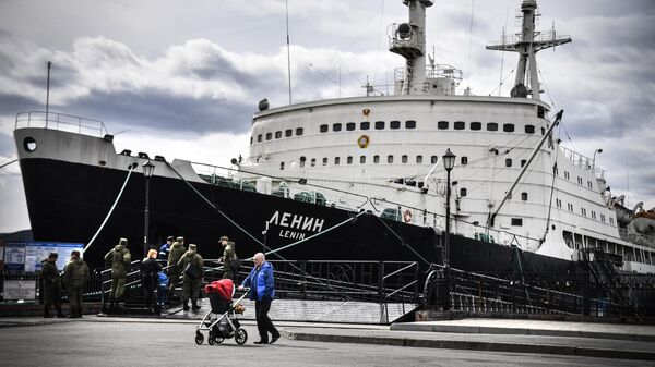 A man pushes a stroller as he walks past a nuclear icebreaker Lenin which is tied up at a moorage in the Russian northern port city of Murmansk on May 19, 2018.  - Sputnik भारत