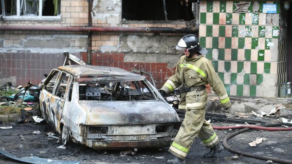 An employee of the Ministry of Emergency Situations of the DPR near a residential building that burned down as a result of shelling of Donetsk by the Armed Forces of Ukraine. - Sputnik भारत
