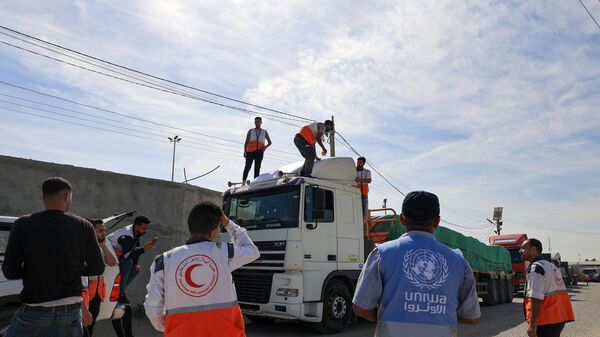 Сотрудники гуманитарных организаций стоят рядом с грузовиками с гуманитарной помощью, въехавшими в сектор Газа из Египта через КПП Рафах  - Sputnik India