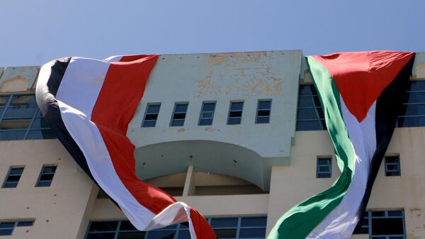 Two large flags, Palestine (L) and Yemen (R), are unfurled off the roof of a building in solidarity with the Palestinians of the West Bank and the Gaza Strip, on the sixth consecutive day of battles between Israel and the Hamas movement in the Gaza Strip enclave, on October 12, 2023, in the Houthi-controlled Yemeni capital Sanaa. - Sputnik भारत
