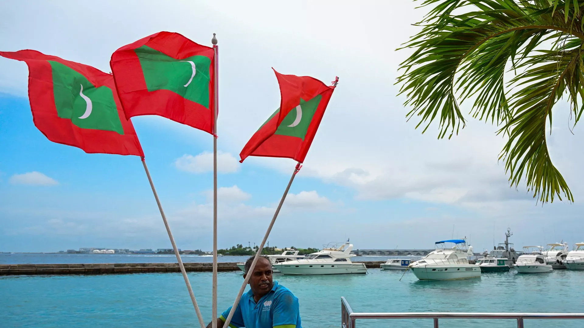 A worker carries national flags of Maldives, ahead of the inauguration of the country's incoming President Mohamed Muizzu in Male on November 14, 2023.