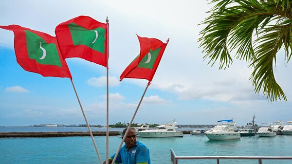 A worker carries national flags of Maldives, ahead of the inauguration of the country's incoming President Mohamed Muizzu in Male on November 14, 2023. - Sputnik भारत