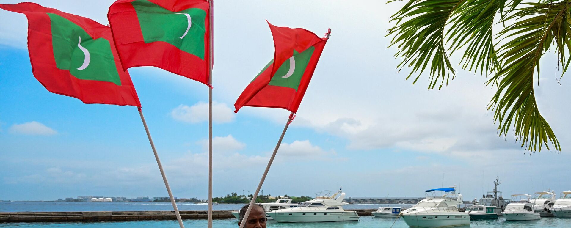 A worker carries national flags of Maldives, ahead of the inauguration of the country's incoming President Mohamed Muizzu in Male on November 14, 2023. - Sputnik भारत, 1920, 19.04.2024