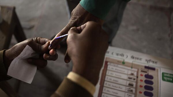 An election official marks the index finger of a voter - Sputnik भारत