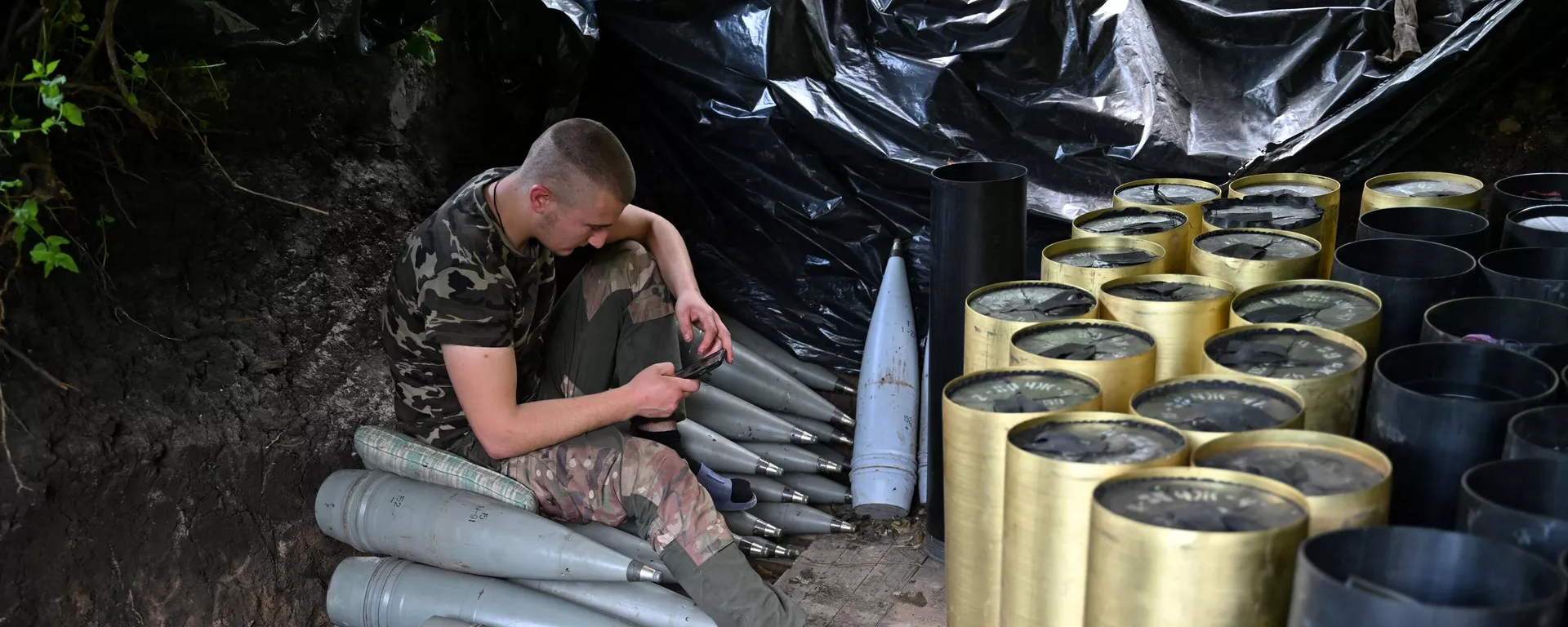 A Ukrainian artilleryman checks his mobile phone next to shells and the cases of propellant charges as he gets a rest at a position near Avdeyevka in the Donetsk region on June 23, 2023. - Sputnik भारत, 1920, 21.11.2023