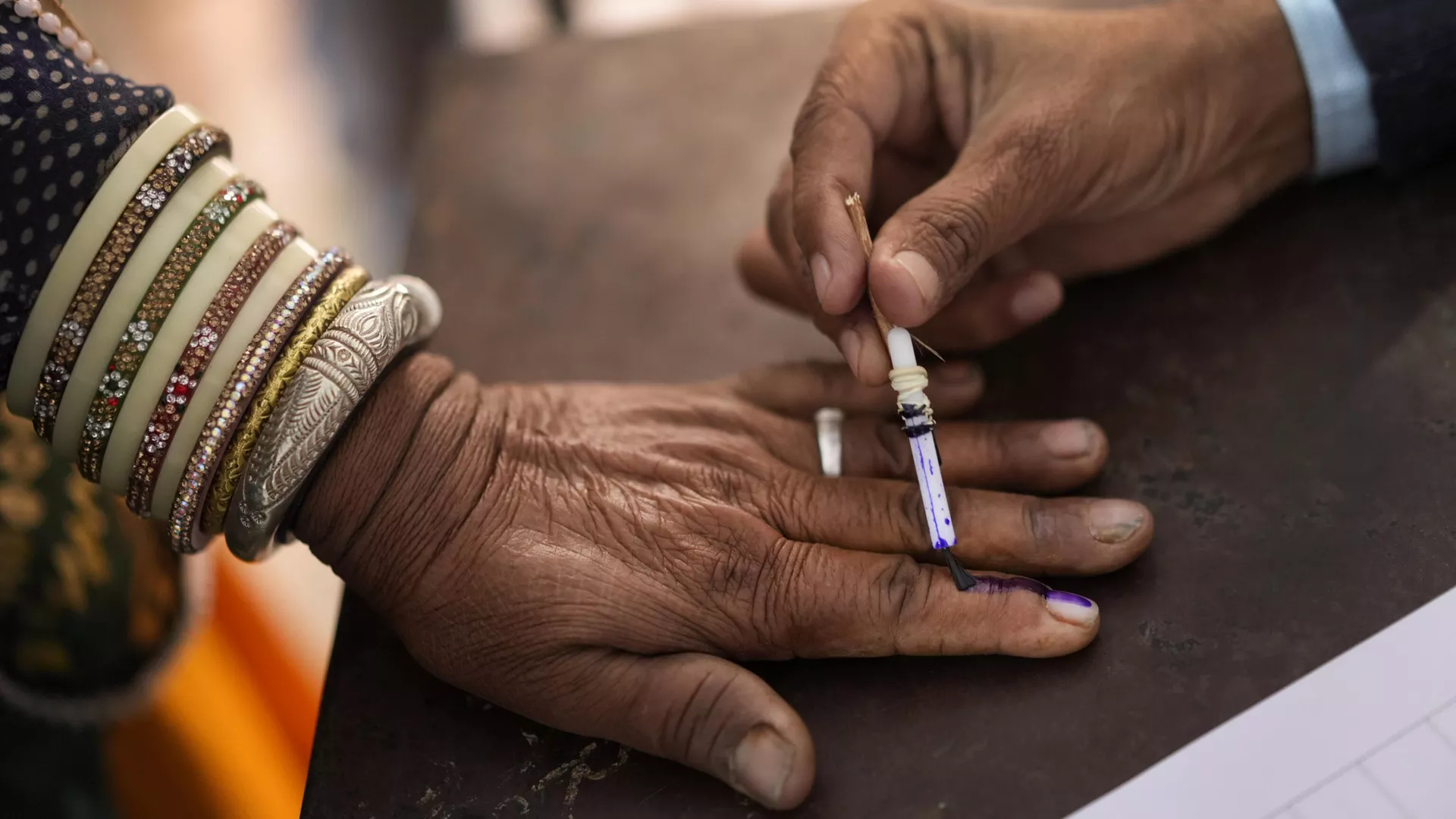 An election officer puts the indelible ink mark on the finger of a voter in Chachiyawas, near Ajmer, India, Saturday, Nov. 25, 2023.