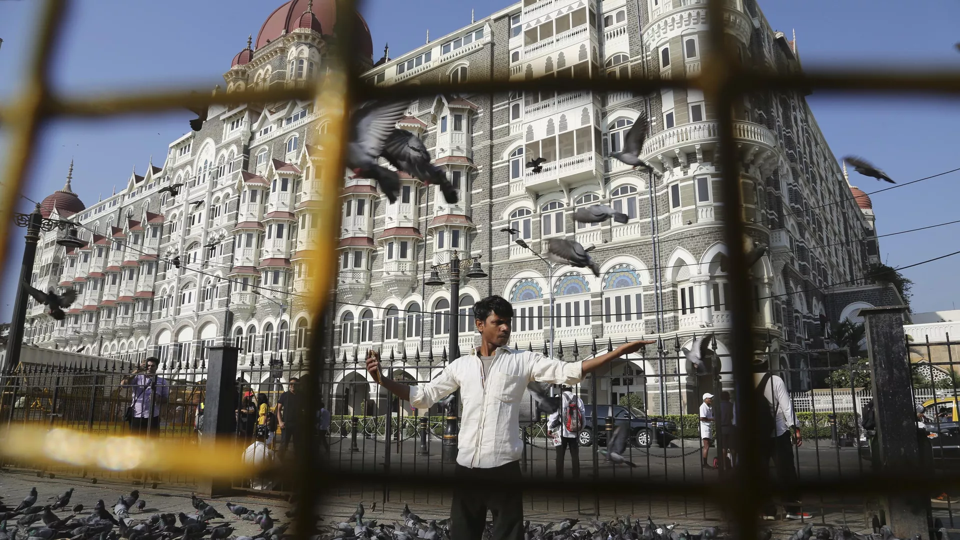 In this Nov 17, 2018, photo, a man feeds pigeons outside the iconic Taj Mahal Palace hotel, the epicenter of the 2008 terror attacks that killed 166 people in Mumbai, India.