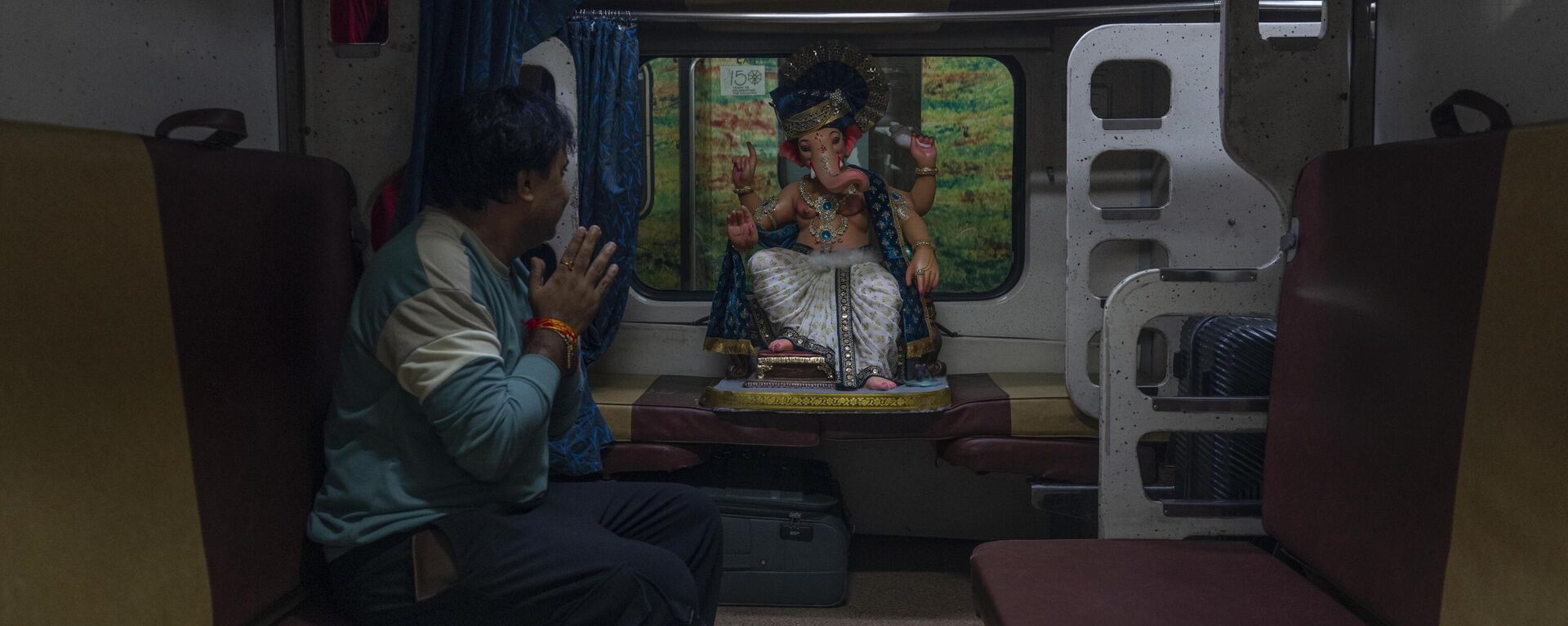 A Hindu devotee gestures respectfully towards a clay idol of elephant headed Hindu god Ganesh as he transports the same in a passenger train for worship in Mumbai, India, India, Sunday, Sept. 10, 2023. Devotees will conduct prayers during the 10-day-long Ganesh Chaturti festival, which will end with the immersion of the idols in different water bodies. - Sputnik भारत, 1920, 29.11.2023