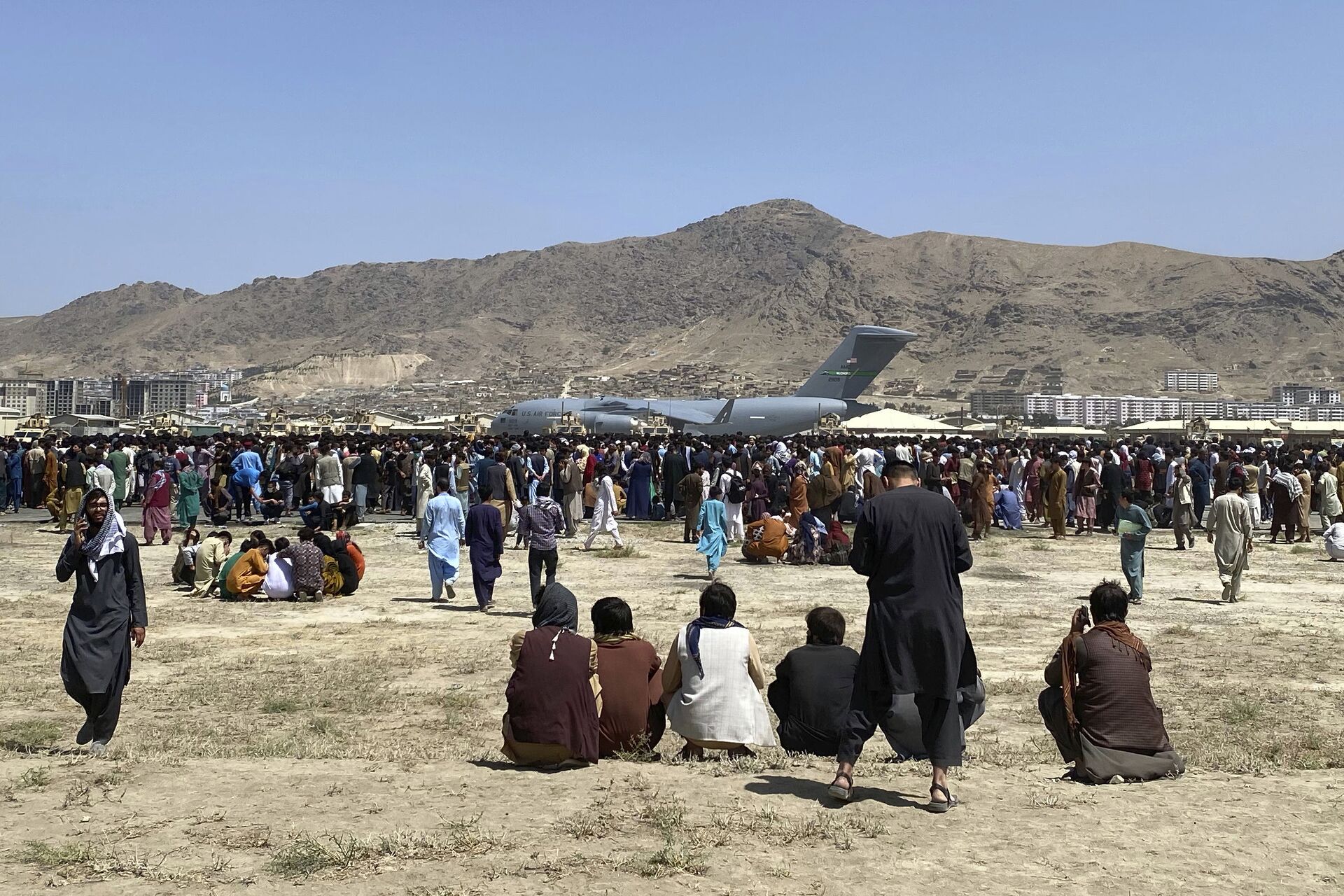 Hundreds of people gather near a U.S. Air Force C-17 transport plane at a perimeter at the international airport in Kabul, Afghanistan, Monday, Aug. 16, 2021. - Sputnik India, 1920, 29.11.2023