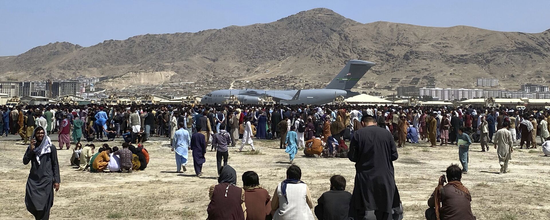 Hundreds of people gather near a U.S. Air Force C-17 transport plane at a perimeter at the international airport in Kabul, Afghanistan, Monday, Aug. 16, 2021. - Sputnik India, 1920, 09.11.2025