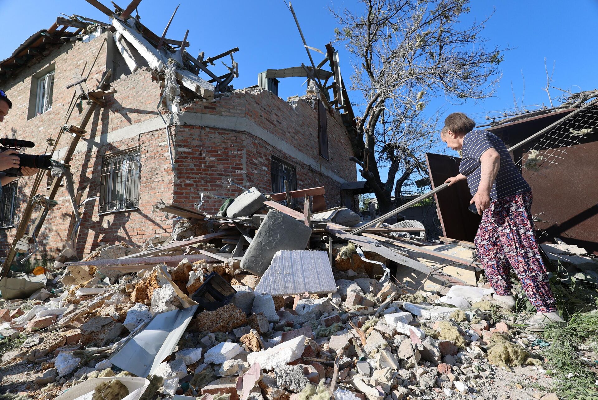 A local resident walks among debris next to a residential house damaged by Ukrainian shelling in the course of Russia's military operation in Ukraine, in Kuibyshev district of Donetsk, Donetsk People's Republic, Russia - Sputnik India, 1920, 30.11.2023