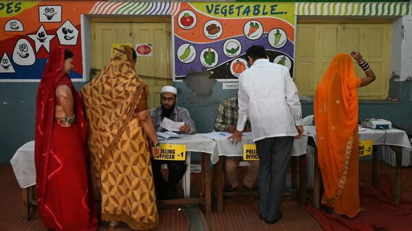 Voters check their names with polling officers prior casting their vote at a polling station during Telangana's state assembly elections in Hyderabad on November 30, 2023. - Sputnik India