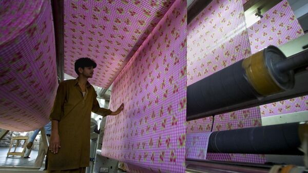  Pakistani worker examines fabric at a textile factory - Sputnik India