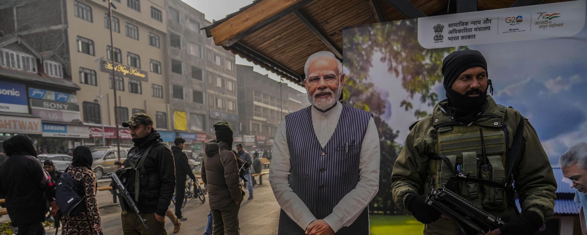 Indian paramilitary soldiers and policemen guard near a cutout portrait of Indian Prime Minister Narendra Modi displayed at the main market in Srinagar, Monday, Dec. 11, 2023. - Sputnik India, 1920, 13.12.2023