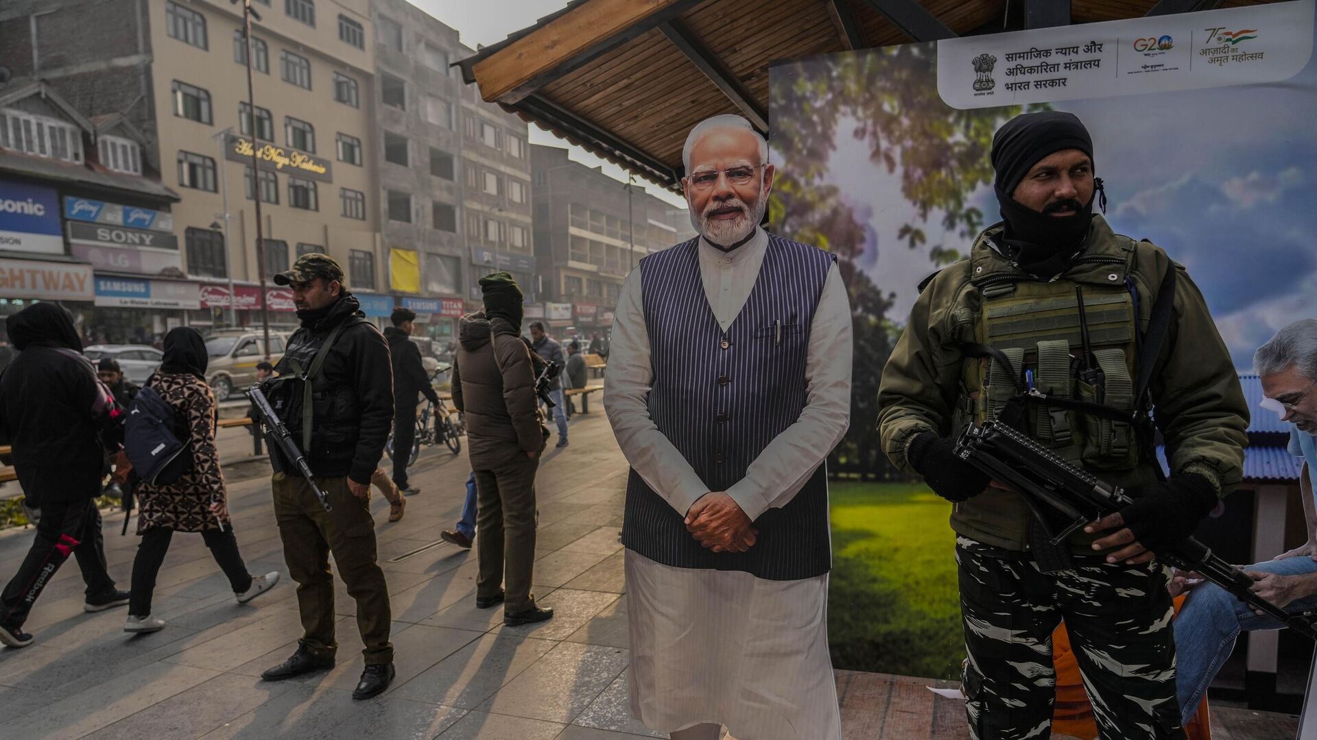 Indian paramilitary soldiers and policemen guard near a cutout portrait of Indian Prime Minister Narendra Modi displayed at the main market in Srinagar, Monday, Dec. 11, 2023. - Sputnik भारत, 1920, 11.12.2023