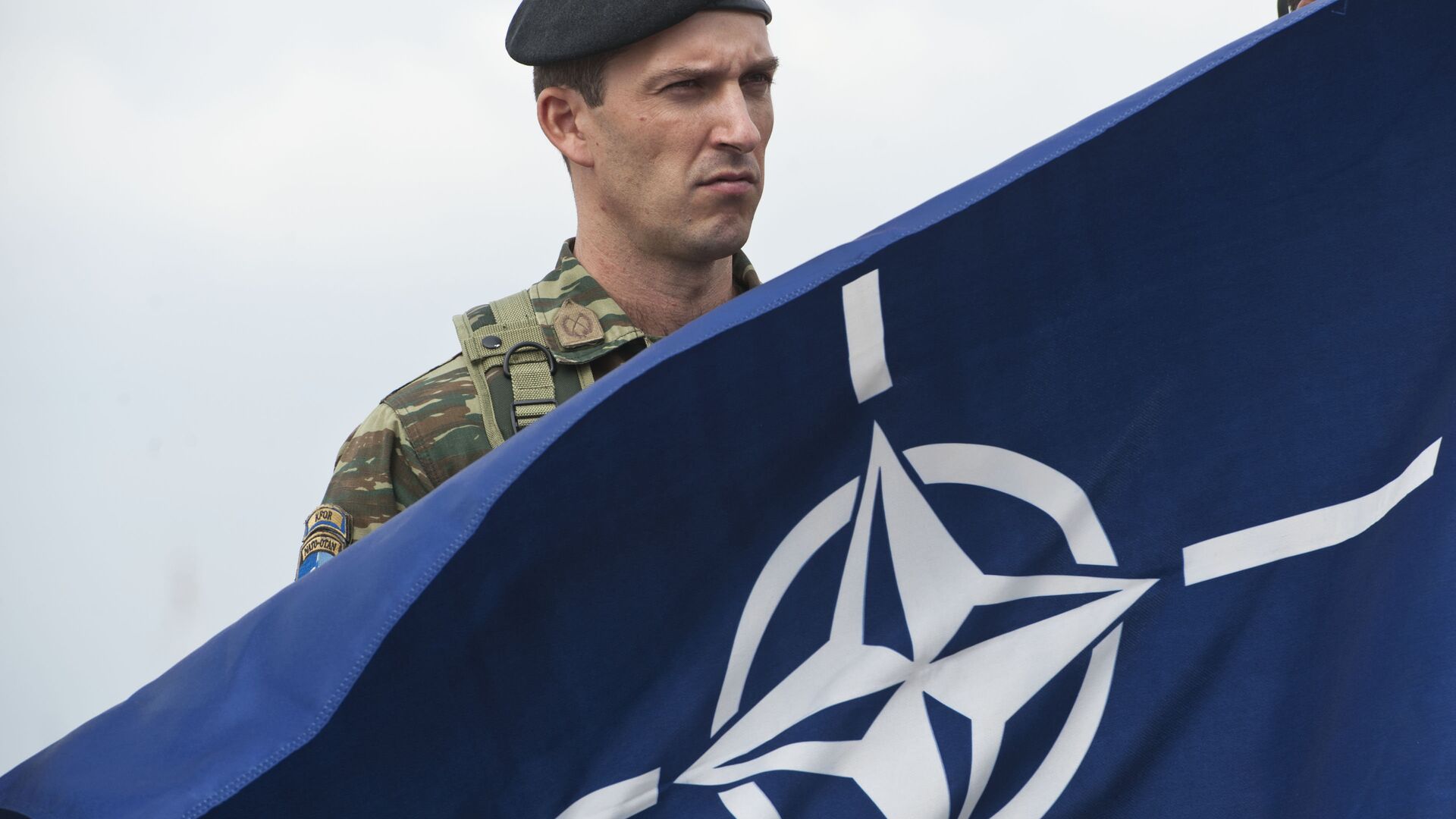 A members of NATO-led peacekeepers in Kosovo (KFOR) holds the NATO flag during the change of command ceremony in Pristina on September 3, 2014 - Sputnik भारत, 1920, 21.12.2023