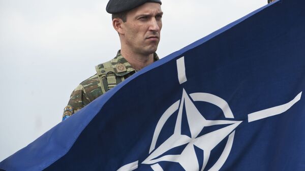 A members of NATO-led peacekeepers in Kosovo (KFOR) holds the NATO flag during the change of command ceremony in Pristina on September 3, 2014 - Sputnik भारत