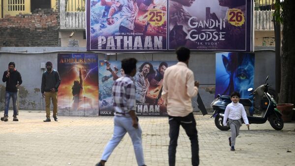 Moviegoers walk past a poster of the Bollywood movie 'Pathaan' outside a cinema hall in Prayagraj on January 25, 2023. - Sputnik India
