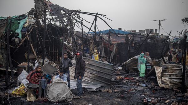 Slum dwellers sit next to the debris of their shanty after a fire broke out in New Delhi, India, Saturday, Jan. 23, 2021. - Sputnik India