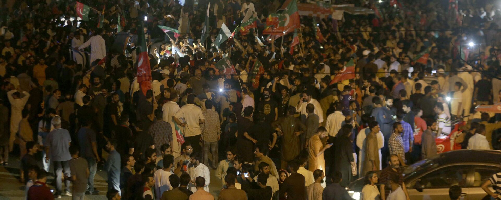 Supporters of former Pakistani Prime Minister Imran Khan's 'Pakistan Tehreek-e-Insaf' party block a road as protests against the provincial assembly's deputy speaker, Dost Mohammad Mazari, for his ruling to invalidate 10 votes in the chief minister elections, in Lahore, Pakistan, Friday, July 22, 2022.  - Sputnik India, 1920, 26.11.2024