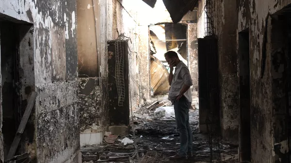 In this Friday, Oct. 16, 2015 photo, an employee of Doctors Without Borders walks inside the charred remains of their hospital after it was hit by a U.S. airstrike in Kunduz, Afghanistan - Sputnik भारत