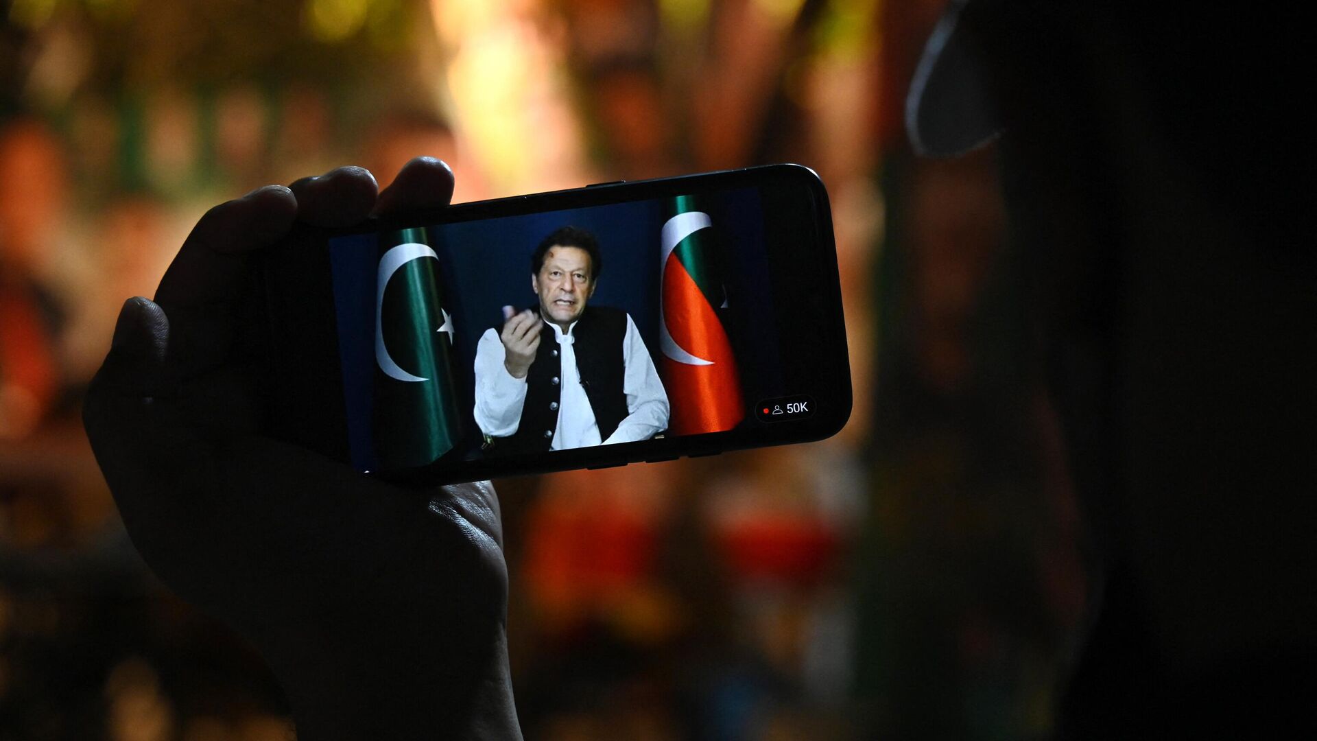 An activist of Tehreek-e-Insaf (PTI) party listens to Pakistan's former Prime Minister Imran Khan's speech on a phone, in Zaman Park in Lahore on May 13, 2023. - Sputnik भारत, 1920, 10.02.2024