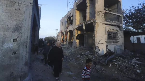 Palestinians walk by a residential building destroyed in an Israeli strike in Rafah, Gaza Strip, Sunday, Feb. 11, 2024 - Sputnik भारत