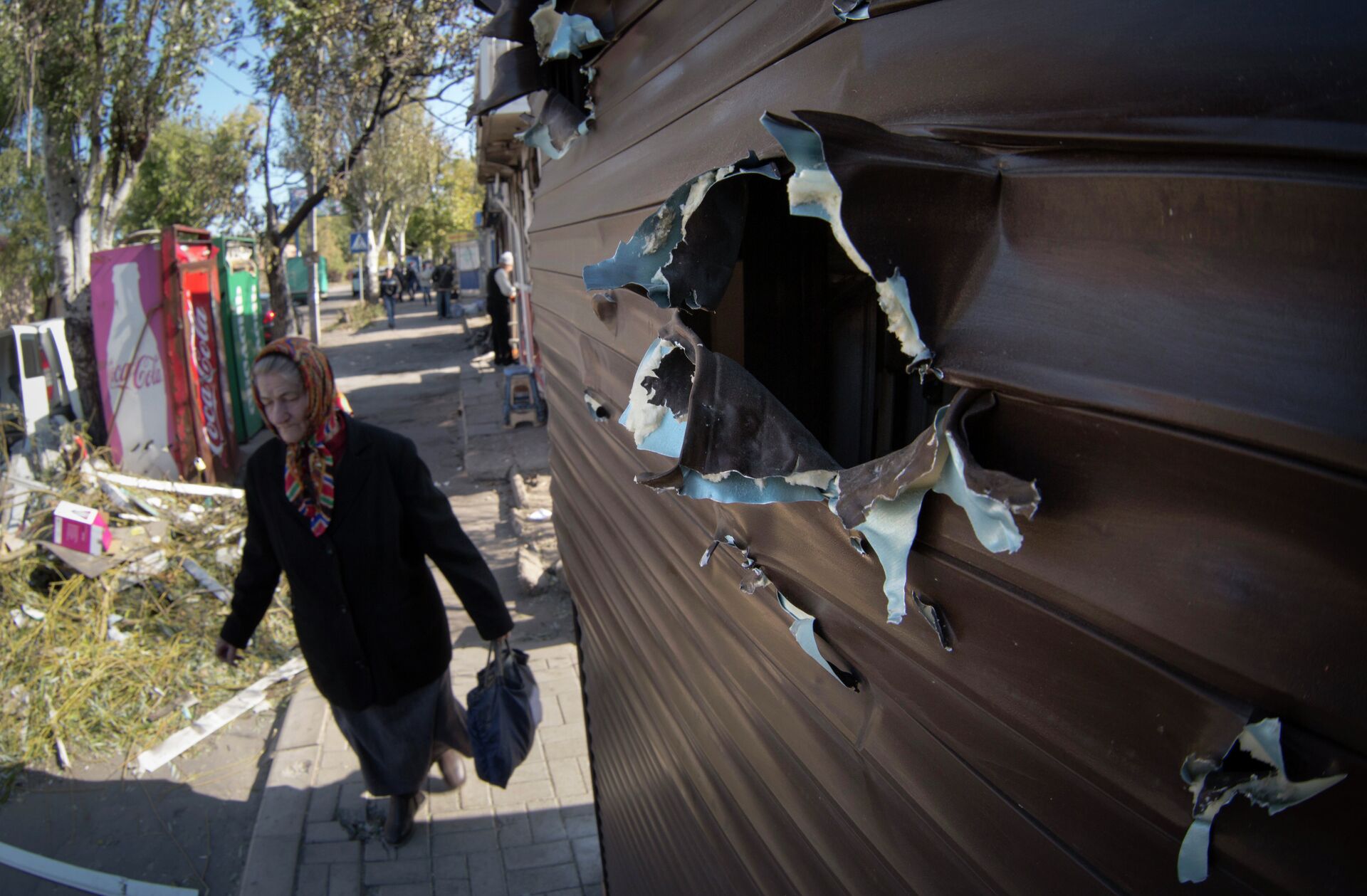 An elderly woman walks past a kiosk damaged by shrapnel at a street market after shelling in the town of Donetsk, eastern Ukraine Friday, Oct. 10, 2014 - Sputnik भारत, 1920, 19.02.2024