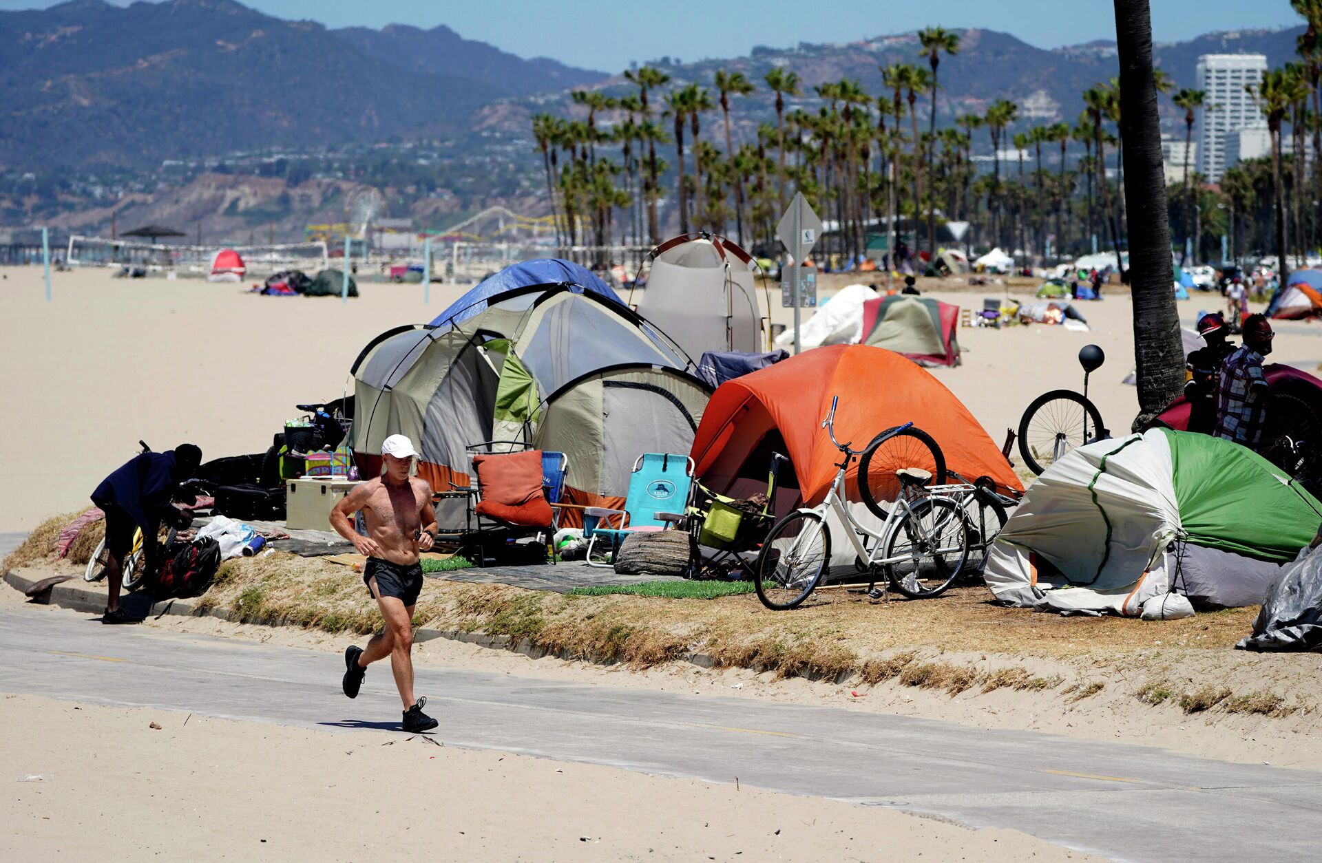  In this June 8, 2021, file photo, a jogger runs past a homeless encampment in the Venice Beach section of Los Angeles. California Gov. Newsom on Thursday, Sept 16, 2021, approved two measures to slice through local zoning ordinances as the most populous state struggles with soaring home prices, an affordable housing shortage and stubborn homelessness. Newson signed the most prominent legislation despite nearly 250 cities objecting that it will, by design, undermine local planning and control. - Sputnik India, 1920, 23.02.2024