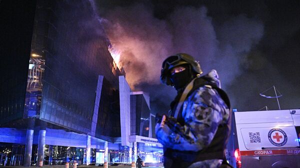 A law enforcement officer is seen near the burning Crocus City Hall concert venue following a reported shooting incident, near Moscow, Russia. - Sputnik भारत