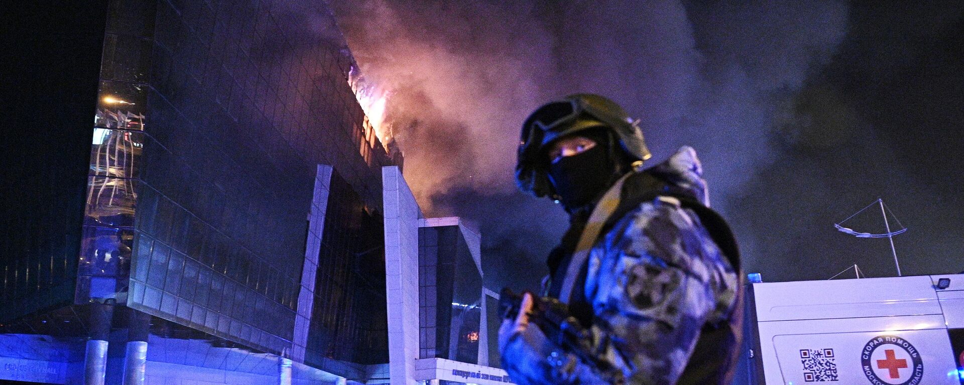 A law enforcement officer is seen near the burning Crocus City Hall concert venue following a reported shooting incident, near Moscow, Russia. - Sputnik India, 1920, 27.03.2024