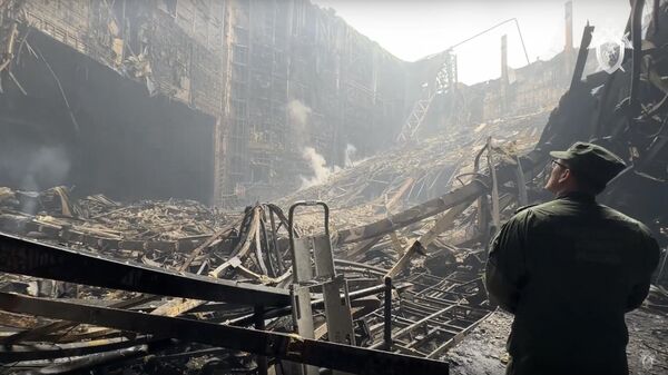 In this grab taken from video released by Investigative Committee of Russia on Saturday, March 23, 2024, an investigators from the Investigative Committee of Russia examines the burned concert hall after an attack on the building of the Crocus City Hall on the western edge of Moscow, Russia. - Sputnik भारत