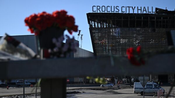 Flowers and toys are placed on the roadside in front of the burnt-out Crocus City Hall following a terrorist attack - Sputnik India