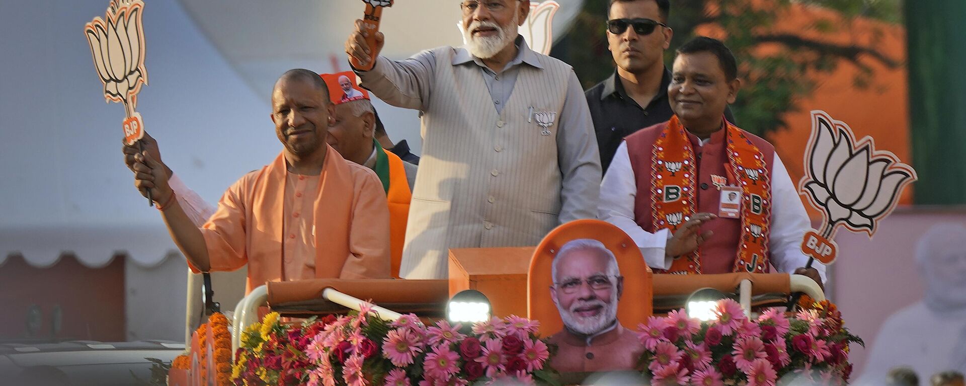 Indian Prime Minister Narendra Modi, center, in a saffron cap, and Chief Minister of Uttar Pradesh Yogi Adityanath, left, in saffron robes, ride in an open vehicle as they campaign for Bharatiya Janata Party (BJP) for the upcoming parliamentary elections in Ghaziabad, India, Saturday, April 6, 2024.  - Sputnik भारत, 1920, 08.06.2024