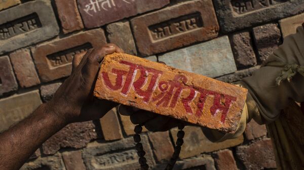 In this Sunday, Nov. 25, 2018, photo, a man holds a brick reading Jai Shree Ram (Victory to Lord Ram) as bricks of the old Babri Mosque are piled up in Ayodhya, in the central Indian state of Uttar Pradesh. - Sputnik India
