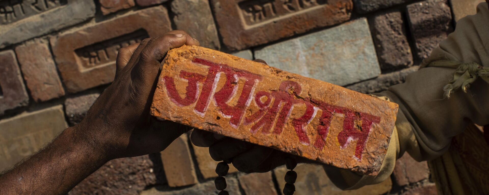 In this Sunday, Nov. 25, 2018, photo, a man holds a brick reading Jai Shree Ram (Victory to Lord Ram) as bricks of the old Babri Mosque are piled up in Ayodhya, in the central Indian state of Uttar Pradesh. - Sputnik भारत, 1920, 19.04.2024
