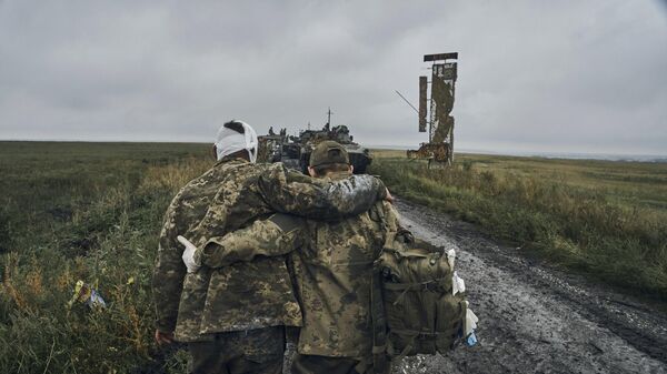 A Ukrainian soldier helps a wounded fellow. File photo - Sputnik भारत