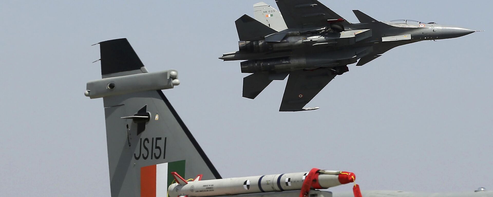 A Sukhoi Su-30 MKI flies over a Jaguar fighter aircraft parked at the static display area on the second day of Aero India 2021 at Yelahanka air base in Bengaluru, India, Thursday, Feb. 4, 2021. - Sputnik भारत, 1920, 22.04.2024