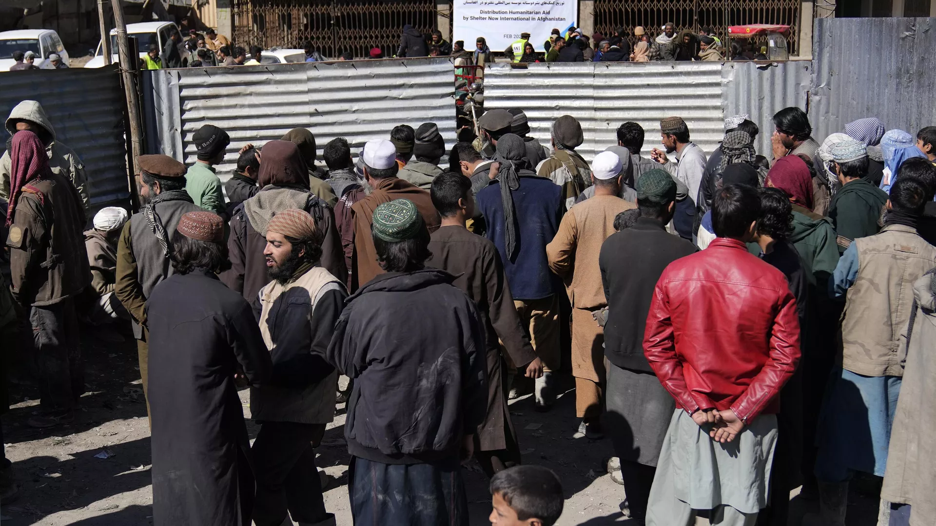 Afghans wait to receive food supplies during a distribution of humanitarian aid for families in need, in Kabul, Afghanistan, Wednesday, Feb. 16, 2022.