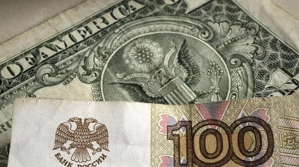 One hundred rubles banknote is pictured in front of a one US dollar banknote, Gelsenkirchen, Germany, Monday, April 25, 2022.  - Sputnik भारत