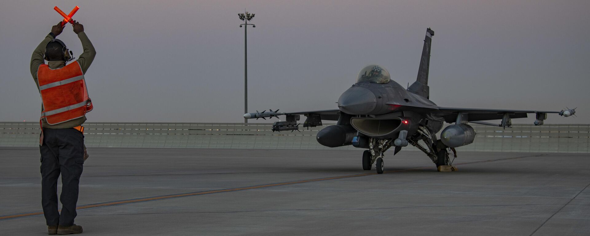 In this handout photo from the U.S. Air Force, an airman guides an F-16 Fighting Falcon during training at Al-Udeid Air Base, Qatar, Jan. 24, 2022.  - Sputnik India, 1920, 30.05.2024
