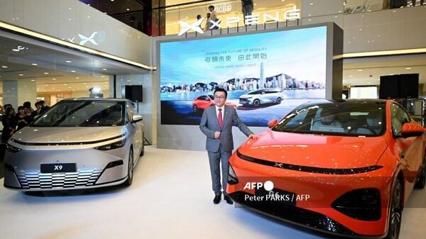 Brian Gu, co-president of Xpeng Inc. has his photo taken next to a Xpeng G6 and X9 electric cars in Hong Kong on May 17, 2024 during the launch of Xpeng vehicles into the city for the first time. (Photo by Peter PARKS / AFP) - Sputnik India