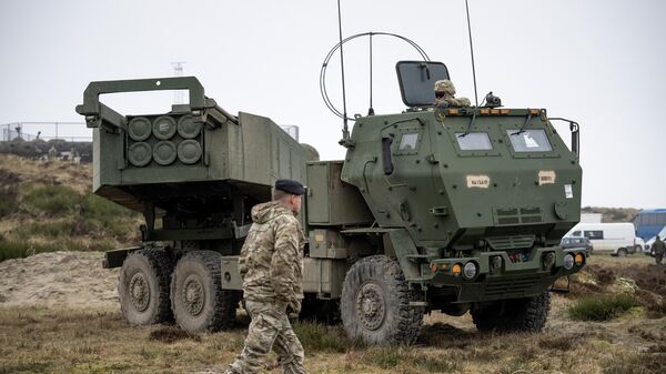 A soldier walks in front of a M142 HIMARS High Mobility Artillery Rocket System during the Dynamic Front military exercise led by the United States at the Oksboel Training and Shooting Range in Oksbol, Denmark on March 30, 2023. - Sputnik भारत