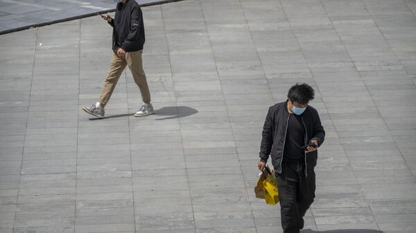 People wearing face masks walk across a plaza at a shopping and office complex in Beijing, Friday, April 28, 2023. - Sputnik भारत