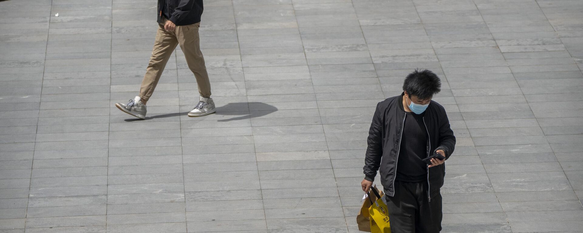 People wearing face masks walk across a plaza at a shopping and office complex in Beijing, Friday, April 28, 2023. - Sputnik भारत, 1920, 17.06.2024