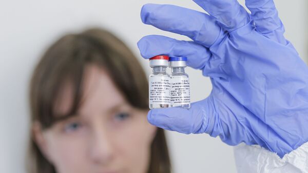 In this handout photo released by Russian Direct Investment Fund and the Gamaleya Scientific Research Institute of Epidemiology and Microbiology, a scientist holds phials of the world's first coronavirus vaccine registered in Russia, in Moscow, Russia.  - Sputnik भारत