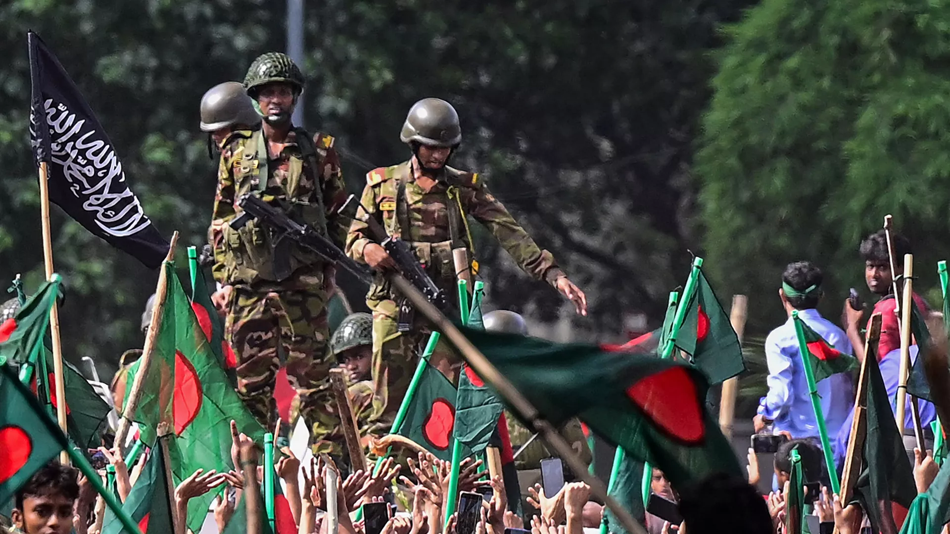 Anti-government protestors march towards Prime Minister Sheikh Hasina's palace as army personnel (C) stand guard in Shahbag area, near Dhaka university in Dhaka on August 5, 2024.